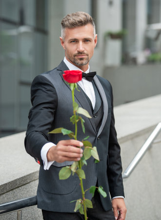 elegant man in black tuxedo. man wearing tuxedo outdoor. tuxedo man with rose. selective focus.の写真素材