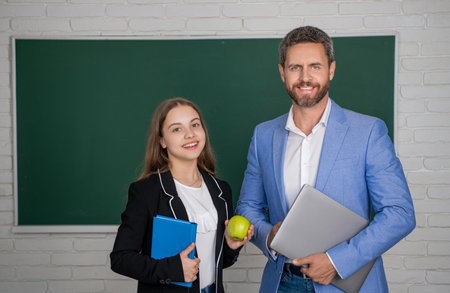 cheerful girl with man teacher in classroom. educationの写真素材
