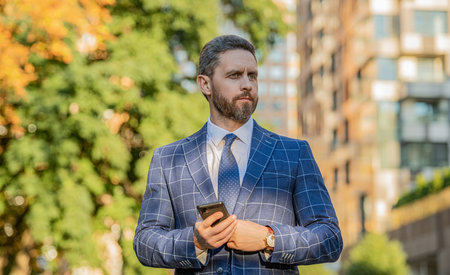 caucasian businessman messaging on phone in the street. businessman messaging on phoneの写真素材