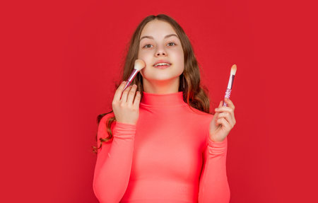 teen child smile apply powder on face with makeup brushの写真素材