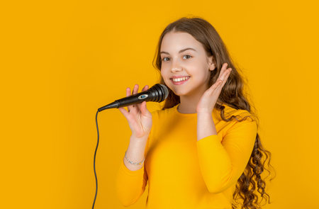 cheerful teen kid with microphone on yellow background