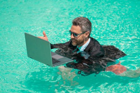 positive man has business video call in weekend refreshing at pool. man has business video callの写真素材