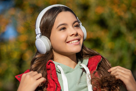 smiling teen girl listening music outside. teen girl listening music wearing headphones.の写真素材