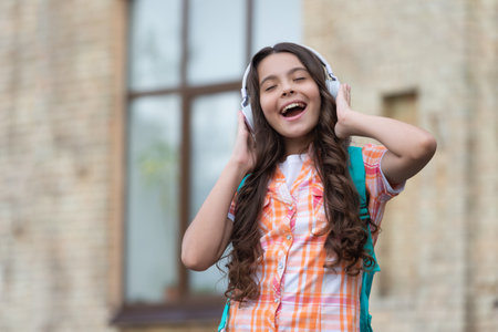 singing school girl listen music outside. photo of school girl listen music.の写真素材