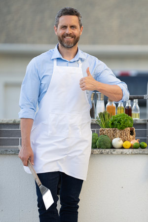 chef man at barbecue and grill, thumb up. chef man at barbecue and grill hold utensil.の写真素材