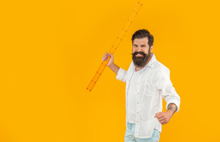 angry man hold school ruler in studio with copy space banner. man hold school ruler