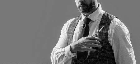 man barbering in barbershop studio, cropped view. bearded man at barbershop. unshaven man hold scissors in barbershop isolated on grey background. man cut hair with barbershop scissors.の写真素材