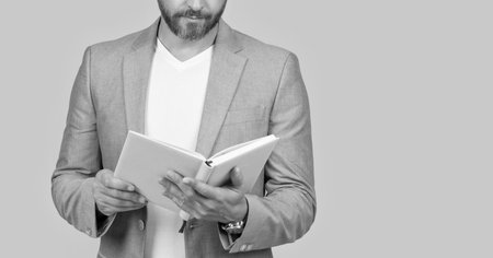 cropped studio shot of businessman holding planner. photo of businessman hold planner. businessman with planner isolated on yellow background. businessman with planner in jacket.の写真素材