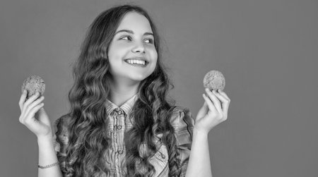 cheerful teen kid with oatmeal cookies on orange background.