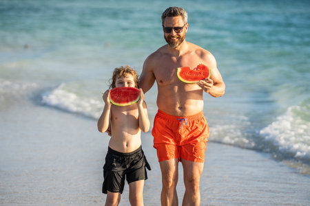 Father dad and son eating watermelon. father and son on summer vacation. single dad father with child son at the beach. Loving father and son enjoying quality time together at sea. summer holidayの写真素材