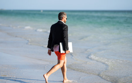Summer weekend and remote freelance work. business man with laptop. Business man dreams on summer in sea. Summer business. Freelancer business man on summer vacationの写真素材