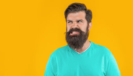 portrait of angry bearded man isolated on yellow copy space banner. portrait of bearded manの写真素材