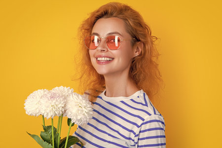 girl in glasses with womens day flowers isolated on yellow. girl with womens day flowersの写真素材