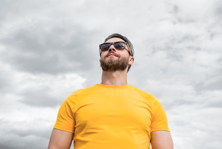 bearded man wearing yellow shirt and sunglasses outdoor on sky background.の写真素材