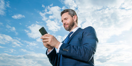cheerful businessman type phone message wear suit. photo of businessman type phone message.の写真素材