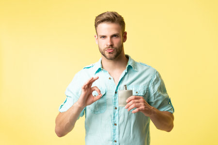 man hold cologne isolated on yellow, ok. man hold cologne in studio background.