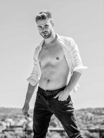 Muscular torso. Muscular sexy macho man. Attractive torso. Hot day outdoors. Attractive man taking off shirt. Confident in his appealing. Bearded guy business style. Black and white. Handsome man fashion model.の写真素材