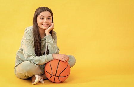 photo of teen basketball girl with ball, copy space. teen basketball girl isolated on yellow.の写真素材