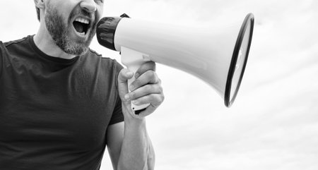 cropped view of man in red shirt shout in loudspeaker on sky background.の写真素材