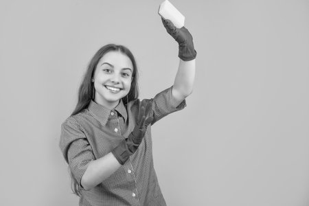 glad child in rubber gloves with sponge on yellow background.の写真素材