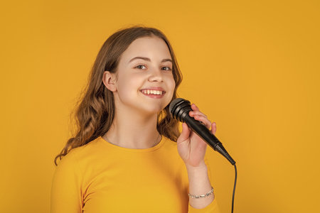 smiling teen child with microphone on yellow backgroundの写真素材