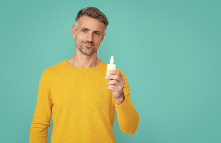man hold nasal medicine isolated on blue. man hold nasal medicine in studio. man hold nasal medicine...