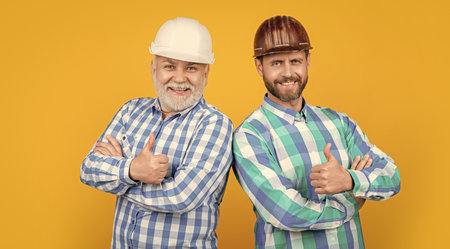 workman generation men on background, thumb up. photo of workman generation men wear building helmet. workman generation men isolated on yellow. workman generation men in studio.の写真素材