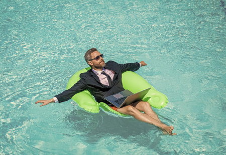 relaxed man trader work and relax. man trader work and relax in swimming pool.の写真素材