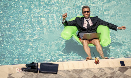 photo of man trader work and relax in pool with laptop, advertisement