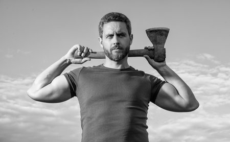 confident man with axe. logger man hold ax. brutal man on sky backgroundの写真素材