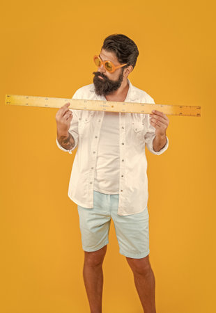 image of man hold measuring ruler. man hold measuring ruler isolated on yellow.