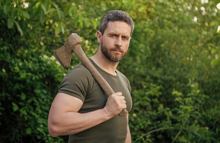 man holding axe outdoor. photo of man with axe. man with axe. man with axe wearing shirt.の写真素材
