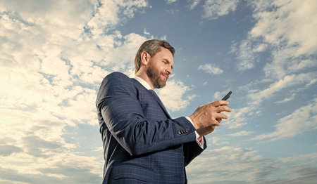 photo of smiling businessman type phone message. businessman type phone message