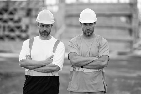 Construction workers at construction site. Serious men wearing safety vests and construction helmetの写真素材