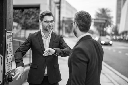 cheerful businessmen check time outdoor at street lightの写真素材