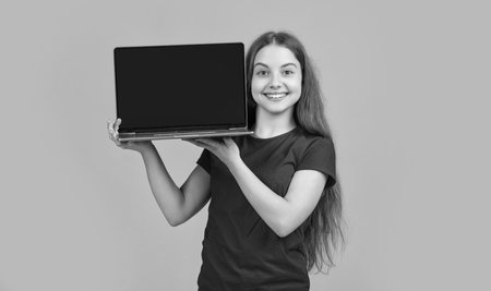 cheerful kid with laptop on yellow backgroundの写真素材