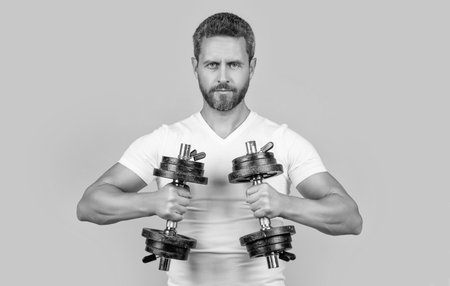 muscular fitness guy training with barbell isolated on yellow. muscular fitness guy training with barbell in studio. muscular fitness guy hold barbell in tshirt. muscular fitness guy with barbell.の写真素材