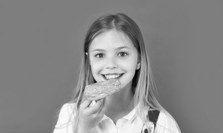 teen girl eating yummy donut isolated on purple. teen girl with yummy donut in studio. teen girl...