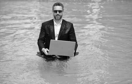 business man working remote with laptop, copy space. photo of business man working remote in summer pool. business man working remote online. business man working remote in swimming pool.の写真素材