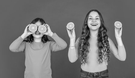 happy teen girls hold orange fruit on pink background.の写真素材