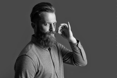 Irish man twirling mustache half turn. Bearded man twisting mustache. Unshaven man with beard and...