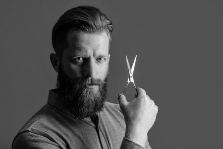 man hold hairdresser scissors for haircut, copy space. concept of mens haircut. man hairdresser do haircut isolated on grey. hairdresser man with scissors to make haircut. man in hairdresser studio.の写真素材