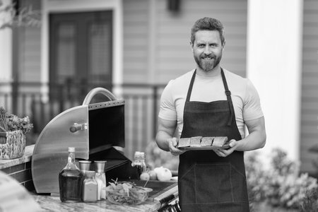 man cook salmon on grill, copy space. chef man cooking salmon on grill outdoor. grill salmon fish at man wear apron. photo of man with grill salmon.の写真素材