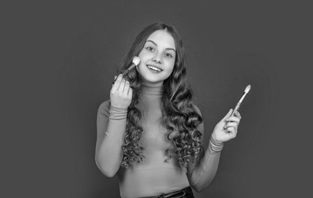 happy teen girl apply powder on face with makeup brush.の写真素材