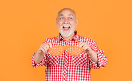 surprised senior man with party glasses on yellow background.