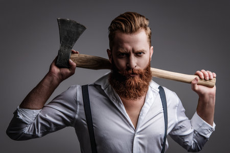 Masculine energy. Retro style. Handsome and charismatic. Masculine man. Masculinity of bearded man with axe isolated on grey. Caucasian brutal man with beard and moustache. Symbol of Maturity.の写真素材