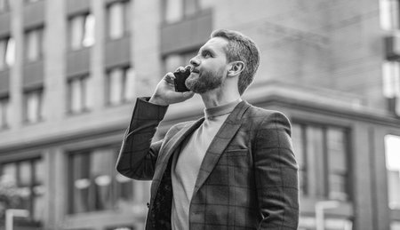 businessman has cellphone call outdoor. businessman having cellphone call in the street. businessman call on cellphone outside. photo of businessman call on cellphone and talk.の写真素材