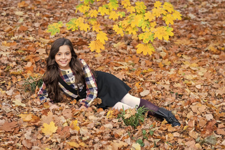 Stylish teen girl at school break. Back to school. Autumn leaves. Girl in fall park wear uniform....