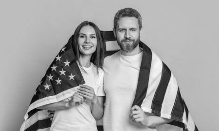 A couple proudly posing with the American flag. Patriotism of couple with the American flag. Celebrating the American spirit couple draped in the flag. American family couple with flagの写真素材