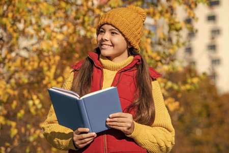 cheerful teen girl read school book in autumn